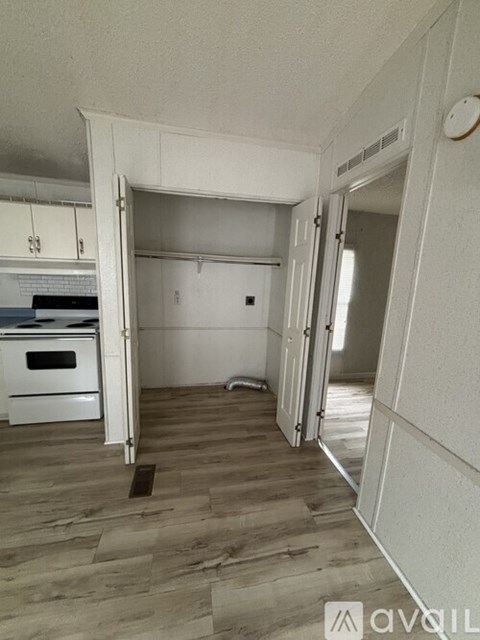 A kitchen with a white oven and wooden flooring.