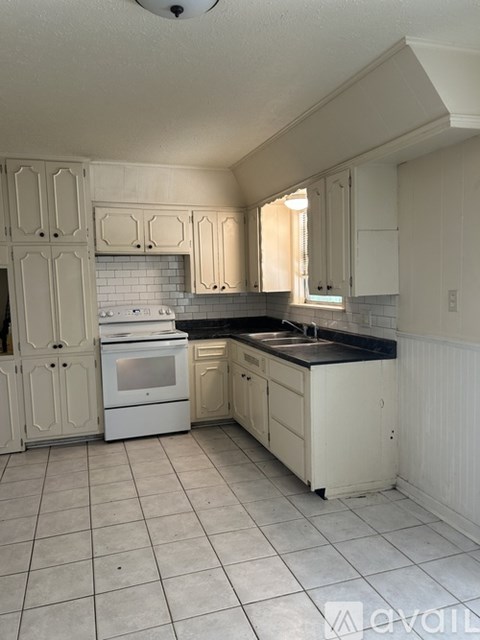 A kitchen with white cabinets and a black countertop.