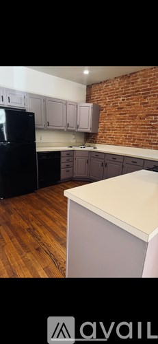 A kitchen with a black fridge and wooden floors.