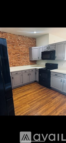 A kitchen with a black fridge and wooden floors.