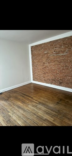 A room with wooden flooring and a brick wall.