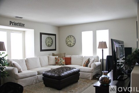 A living room with a white couch and a brown ottoman.