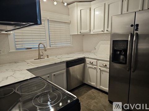 A kitchen with a stove top oven, sink, and refrigerator.