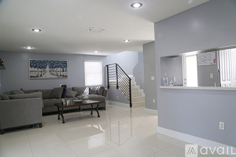 A living room with a grey couch and a painting on the wall.