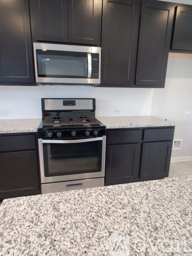 A kitchen with a stove and microwave above it.