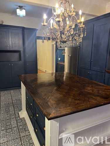 A kitchen with dark blue cabinets and a wooden island.