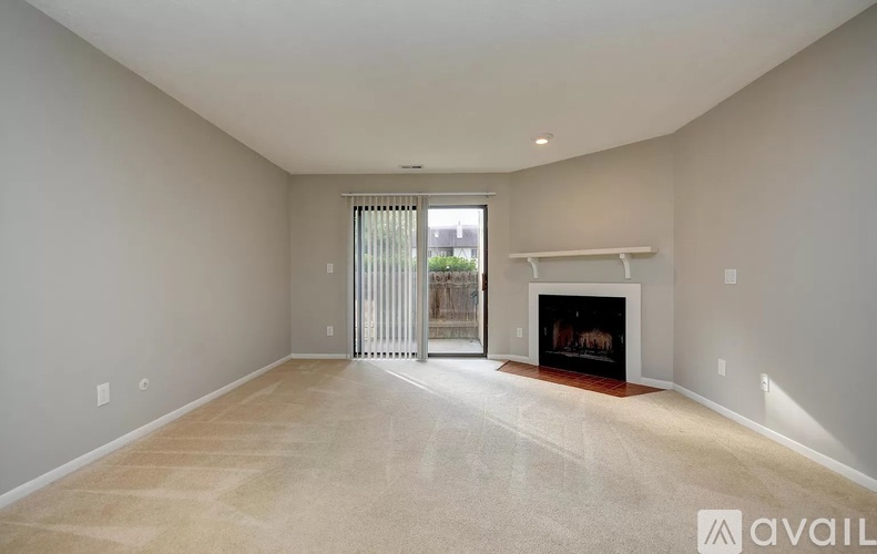 A spacious living room with a fireplace and sliding glass doors leading to a balcony.