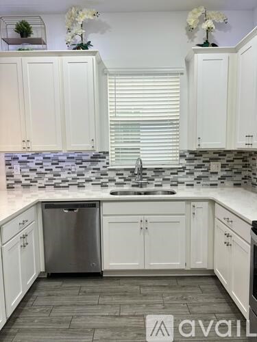 A kitchen with white cabinets and a checkered backsplash.