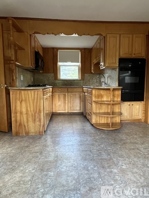 A kitchen with wooden cabinets and a black refrigerator.