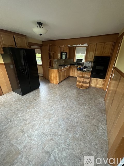 A kitchen with wooden cabinets and a black refrigerator.