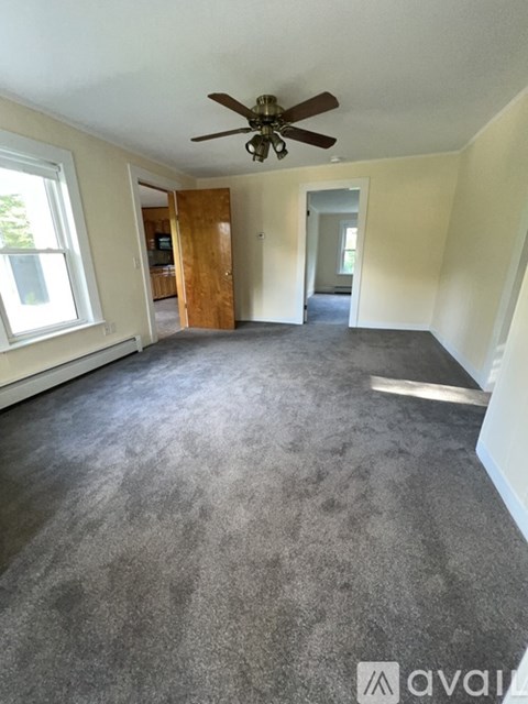 A room with a ceiling fan and carpeted floor.