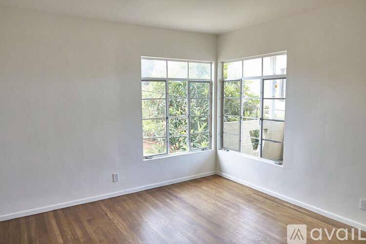 A room with wooden floors and a large window with a view of trees.
