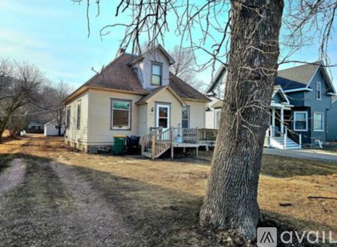 A house with a porch and a tree in front of it.