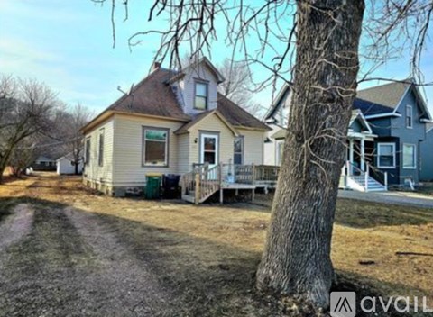 A house with a porch and a tree in front of it.