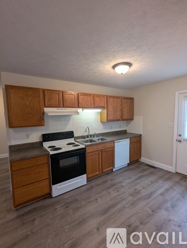 A kitchen with wooden cabinets and a white stove top oven.