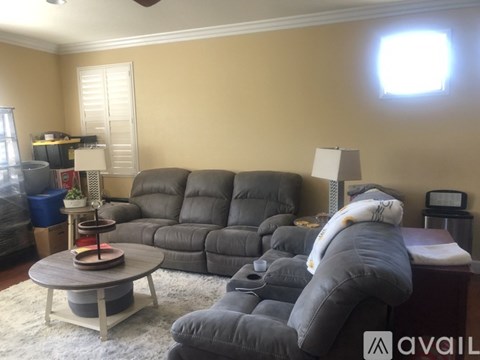 A living room with a grey sofa and a round wooden coffee table.