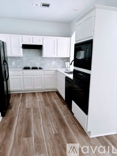 A kitchen with white cabinets and a black stove top oven.