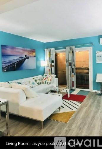 A living room with a white couch and a painting on the wall.