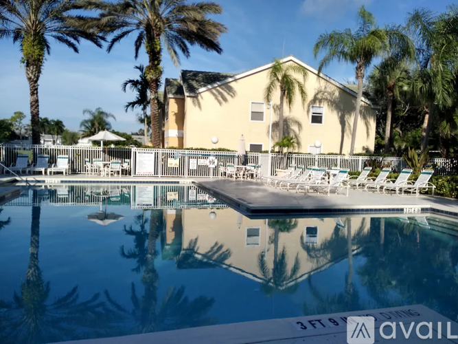 A pool with a building and palm trees in the background.