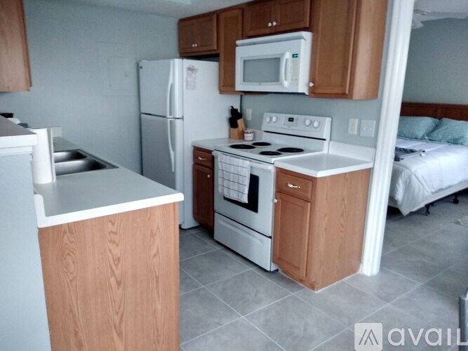 A kitchen with a white stove top oven and white microwave above a white counter.