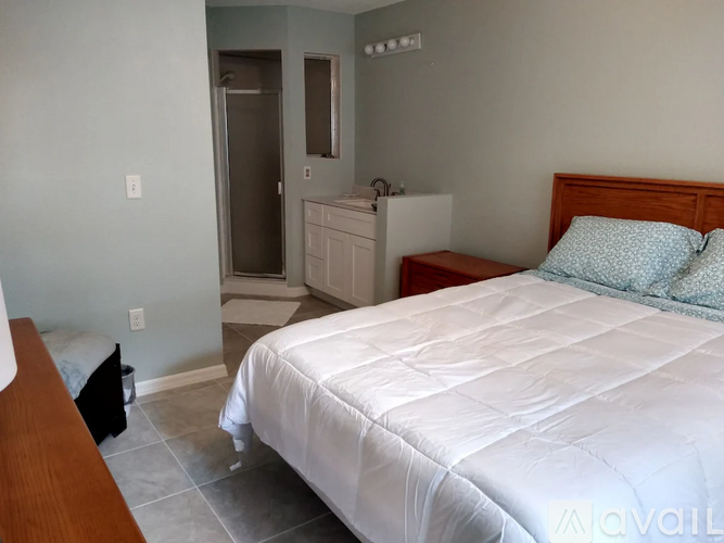 A bedroom with a white bed and a wooden headboard.