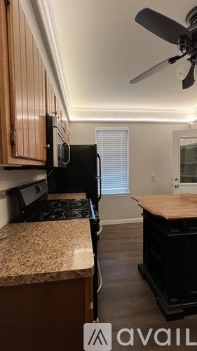 A kitchen with a fan on the ceiling and a microwave on the counter.