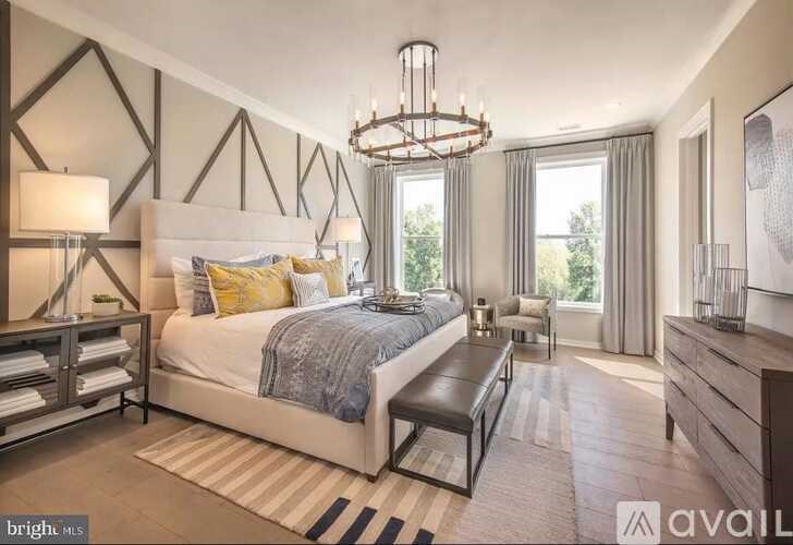 A bedroom with a large bed, a bench, and a chandelier.