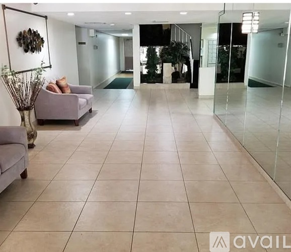 A spacious hallway with a purple couch and a vase with dried plants.