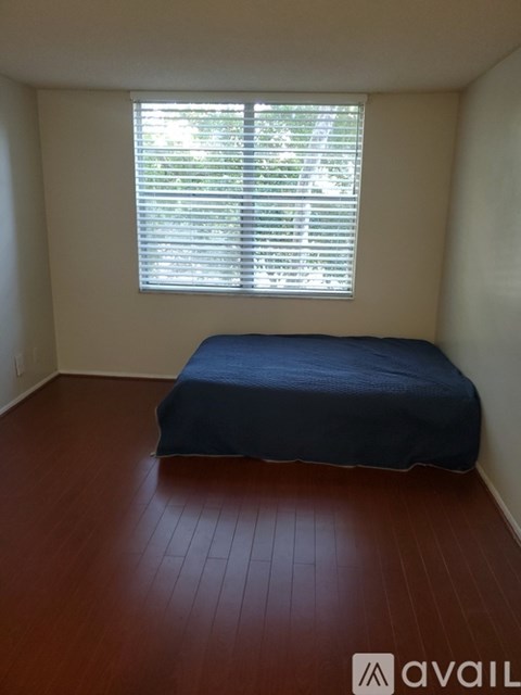 A bedroom with a bed and a window with blinds.