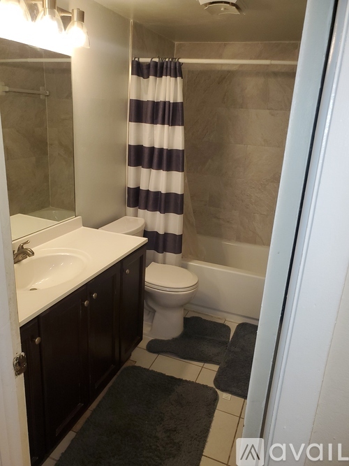 A bathroom with a toilet, sink, and striped shower curtain.