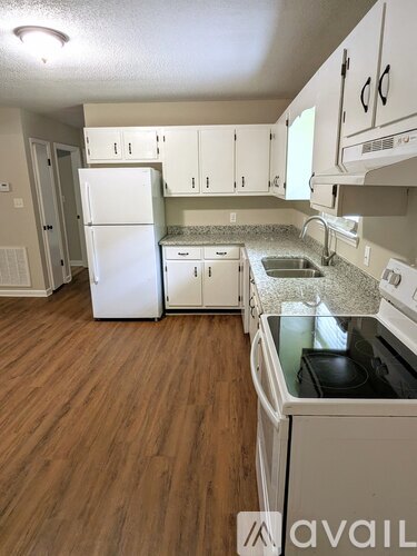 A kitchen with white appliances and wooden floors.