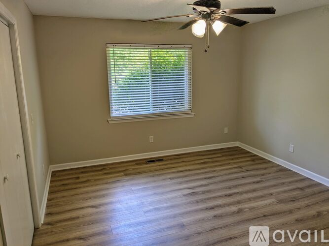 A room with a ceiling fan and a window with blinds.