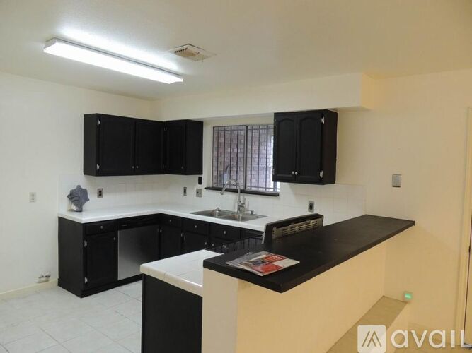 A kitchen with black cabinets and a white countertop.