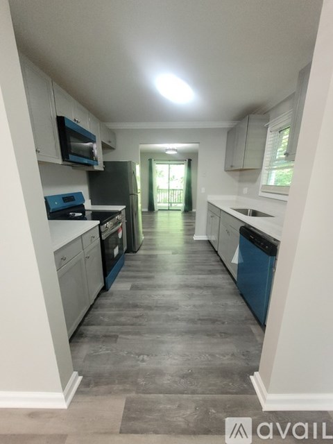 A kitchen with a blue dishwasher and white cabinets.