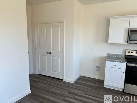 A kitchen with a white door and a microwave above the stove.