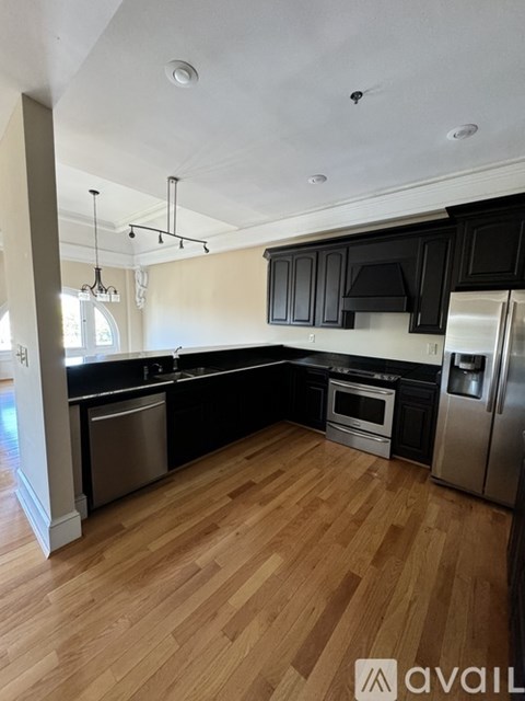 A kitchen with black cabinets and wooden floors.