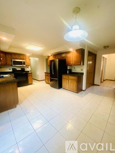 A kitchen with wooden cabinets and a black refrigerator.