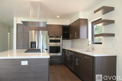 A modern kitchen with dark wood cabinets and stainless steel appliances.