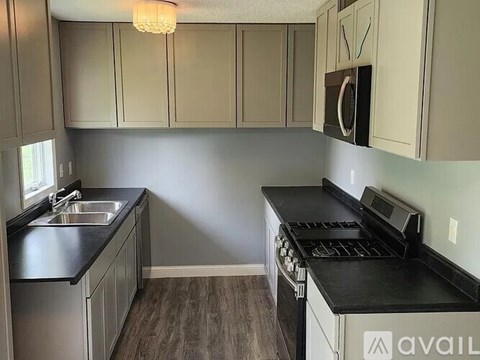 A kitchen with black countertops and a stove top oven.