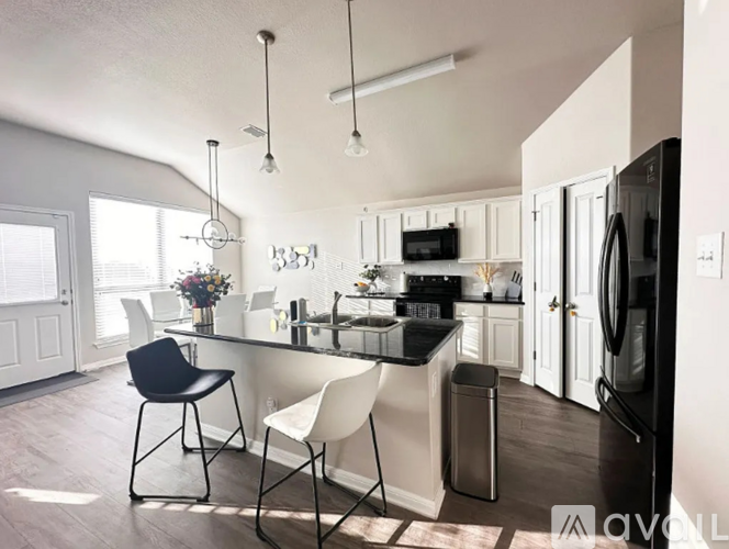A kitchen with a black countertop and white cabinets.