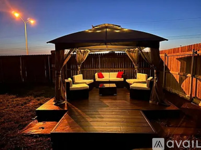 A gazebo with a black roof and white cushions is set up on a wooden deck.