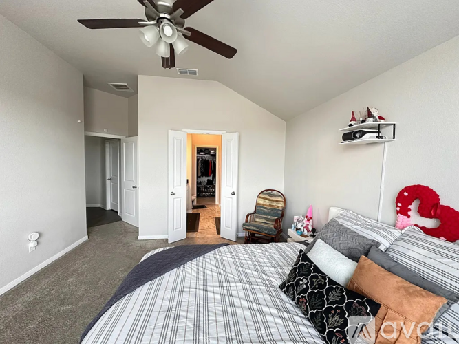 A bedroom with a bed, a ceiling fan, and a chair.