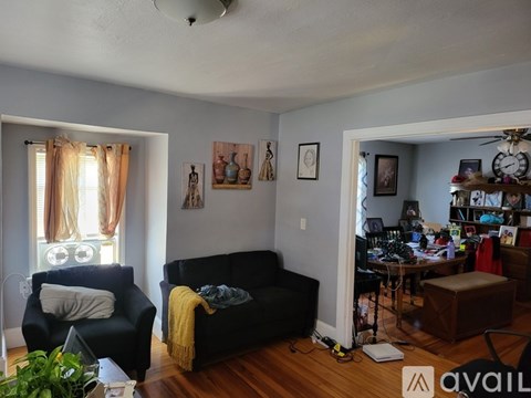 A living room with a black couch and a yellow throw blanket.