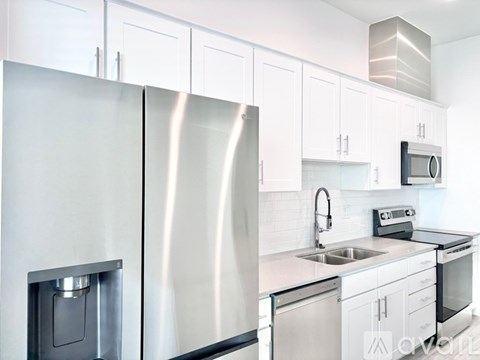 A modern kitchen with a stainless steel refrigerator and white cabinets.