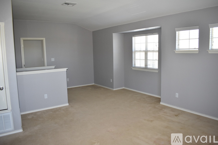 A spacious room with a cabinet and two windows.