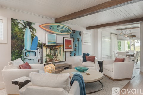 A living room with white furniture and a surfboard mural on the wall.