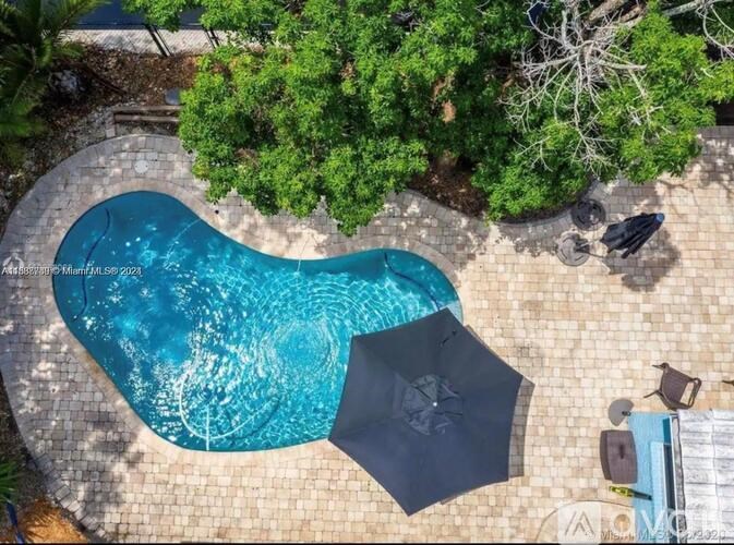 A swimming pool surrounded by trees and a stone patio.