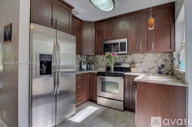 A kitchen with a stainless steel refrigerator and wooden cabinets.
