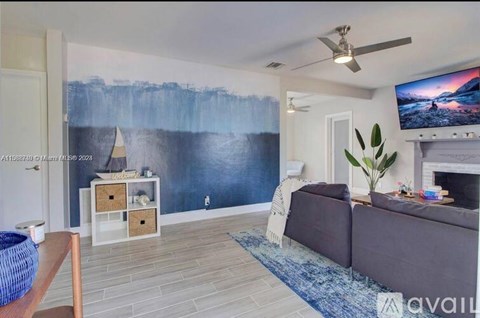 A living room with a large painting on the wall and a flat screen TV mounted above the fireplace.