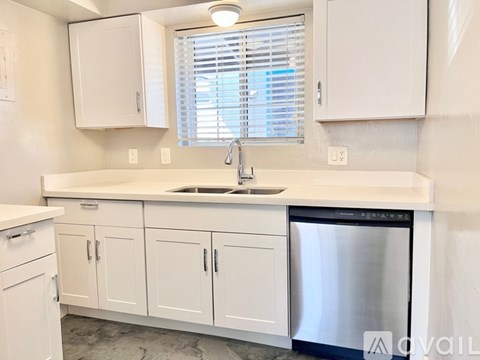 A kitchen with white cabinets and a stainless steel dishwasher.